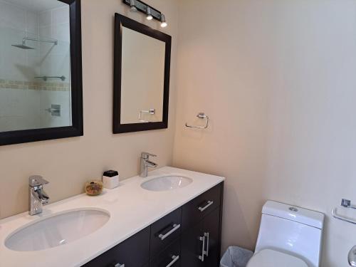 a bathroom with two sinks and a mirror and a toilet at Comfortable villa near the beach in Jolly Harbour
