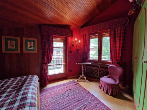 ein Schlafzimmer mit roten Wänden, einem Bett und Fenstern in der Unterkunft APPARTAMENTO SAUZE D'OULX in Sauze dʼOulx