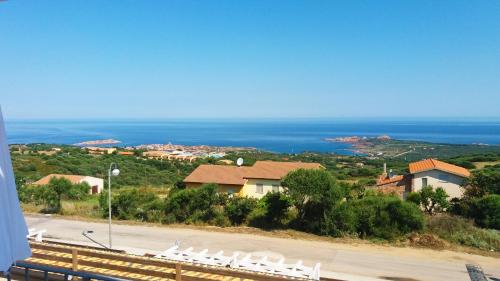 a group of white chairs on a hill with the ocean at Affittimoderni Isola Rossa Elite-PATI24 in Cascabraga