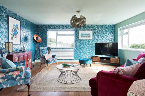 a living room with blue walls and a tv at Pass the Keys Coastal Boutique Luxury Home With Sea Views in Amlwch
