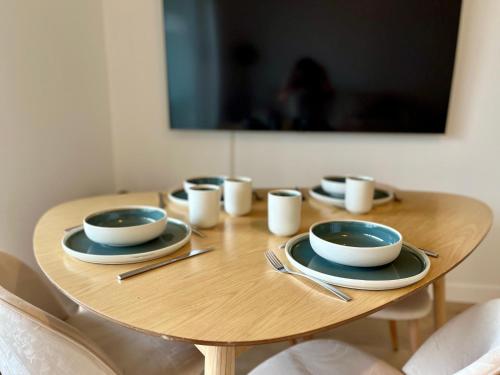 プルゴンヴランにあるAppartement Cosy, terrasse vu mer, piscine, Sauna - WarmHouseの木製テーブル(皿、カップ付)
