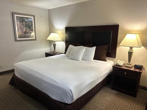 a hotel room with a large bed and two lamps at Sojourn Suites Portland Airport in Portland