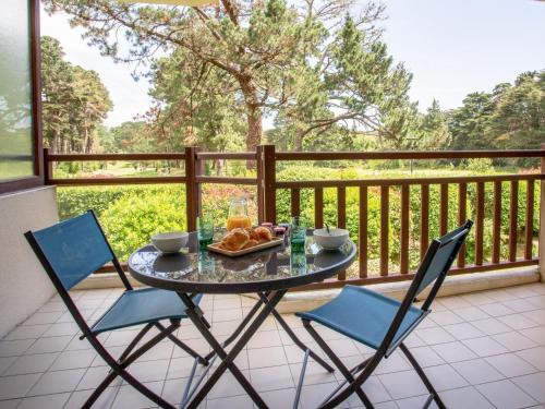 - une table avec deux chaises et un bol de nourriture sur le balcon dans l'établissement Apartment Les Terrasses du Golf by Interhome, à Pornic