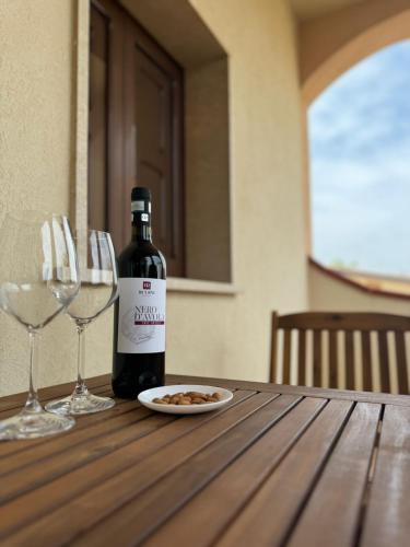 Una botella de vino y dos copas de vino en una mesa de madera. en Cantu d'Amuri, en Avola