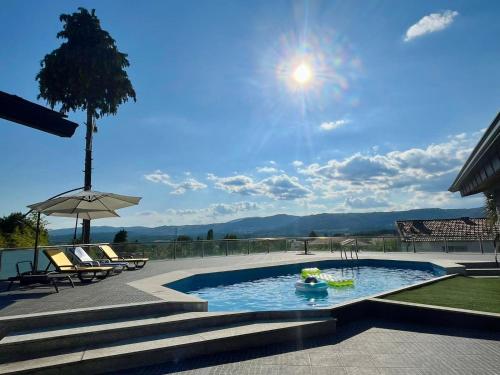a pool with chairs and an umbrella on a patio at Casa da Anta in Chaves