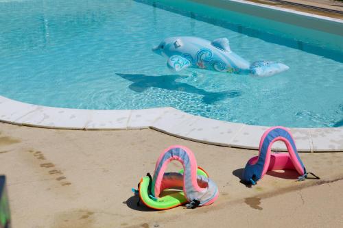 une paire de tongs dans le sable à côté d'une piscine dans l'établissement Chez Lili, à Meslan