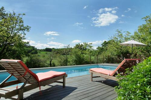 deux chaises et un parasol à côté d'une piscine dans l'établissement Gîte de Berle, à Chauffour-sur-Vell