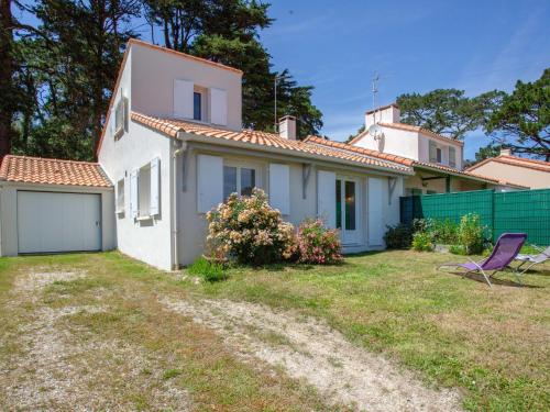 een wit huis met een tuin en een paarse stoel bij Holiday Home Les Pins by Interhome in Pornic