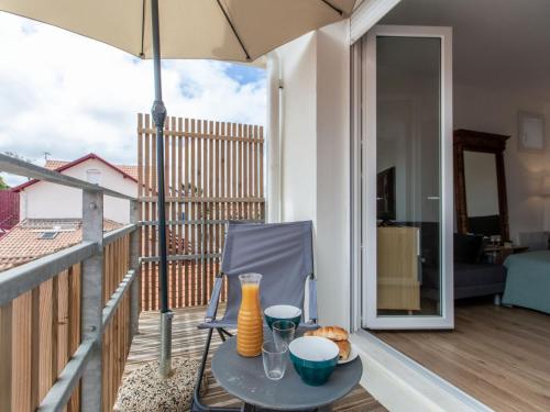d'une table et d'une chaise sur un balcon avec un parasol dans l'établissement Studio Cap Océan-16 by Interhome, à Capbreton
