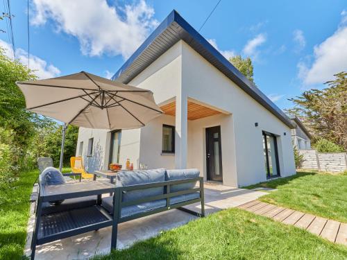 a house with a bench and an umbrella at Holiday Home Les sablons by Interhome in Agon Coutainville