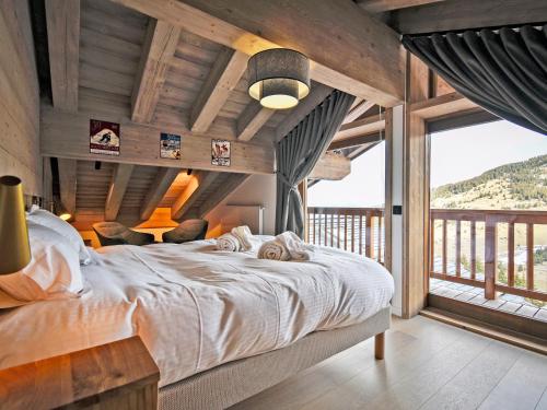 une chambre avec un grand lit et une grande fenêtre dans l'établissement Superbe appartement 143m², 4 chambres, proche des pistes, prestations haut de gamme - FR-1-613-101, à Les Allues
