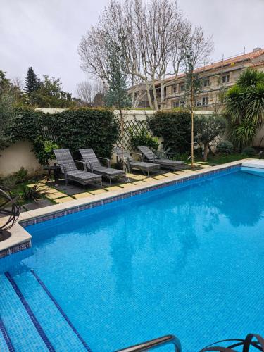 une grande piscine bleue avec des chaises et un bâtiment dans l'établissement Villa Maskali, à Cuxac-dʼAude