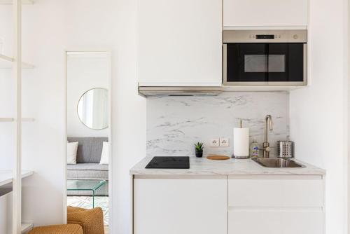 une cuisine blanche avec des armoires blanches et un évier dans l'établissement GuestReady - Charmant studio lumineux à Paris, à Paris