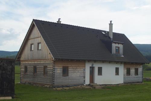 a large wooden house with a black roof at Roubenky za Hurtovnou in Orlické Záhoří 