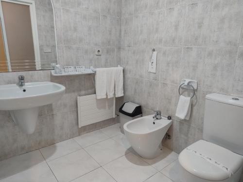 a white bathroom with a sink and a toilet at Motel Montecarlo in Teo