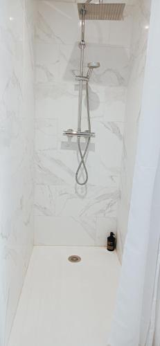 La salle de bains blanche est pourvue d'une douche et de murs en marbre blanc. dans l'établissement Appart' confort à Calais-Nord, à Calais