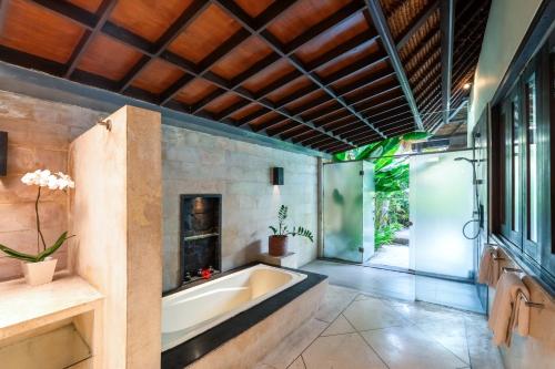 a bathroom with a tub and a fireplace at The Maya Seminyak Villas in Seminyak