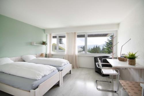 two beds in a room with a desk and a window at B&B Mont-Crosin in Mont-Crosin