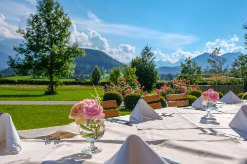 a table with white table cloth and pink flowers in a vase at Villa Sonnwend National Park Lodge in Rossleithen