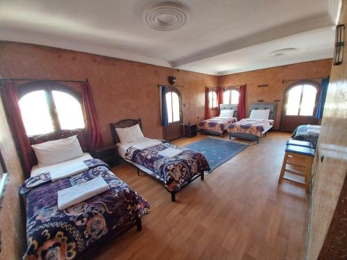 a room with three beds and windows at Sud Est Palace in Aït Ridi