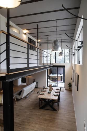 - un grand salon avec une table et un escalier dans l'établissement L'atelier de 1900, à Puicheric