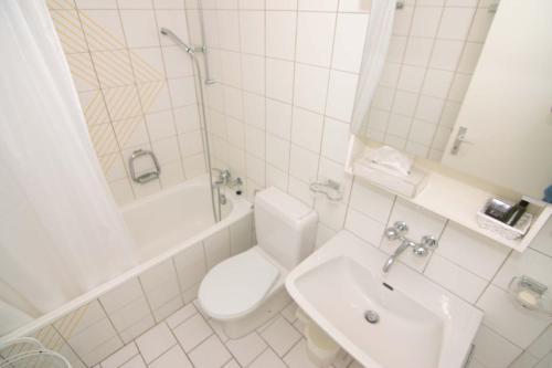 a white bathroom with a toilet and a sink at B&B Mont-Crosin in Mont-Crosin
