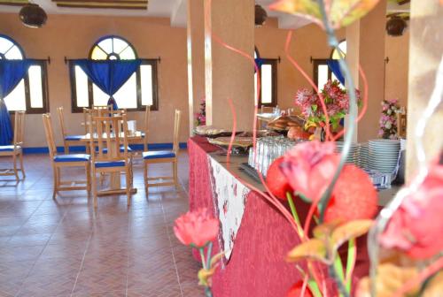 a room with tables and chairs and a counter with flowers at Sud Est Palace in Aït Ridi