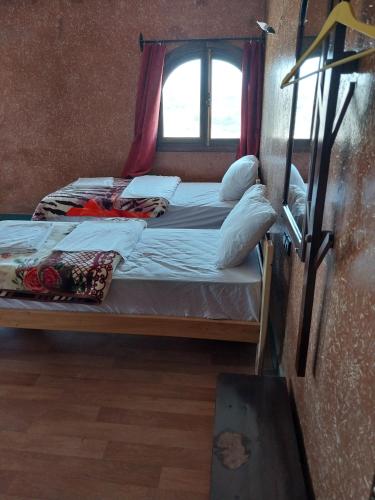 two beds in a room with a window at Sud Est Palace in Aït Ridi