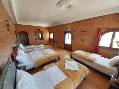 a hotel room with three beds and a room with windows at Sud Est Palace in Aït Ridi