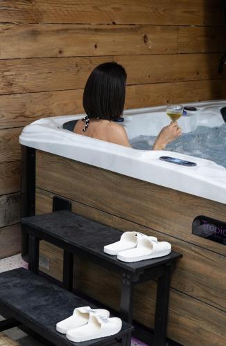 une femme dans une baignoire avec un verre de vin dans l'établissement L'atelier de 1900, à Puicheric