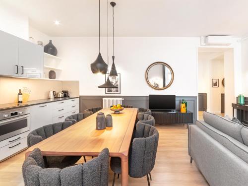 Il dispose d'une cuisine et d'un salon avec une table et des chaises en bois. dans l'établissement LivinParis - Luxury AC 3 Bedrooms Le Louvre I, à Paris