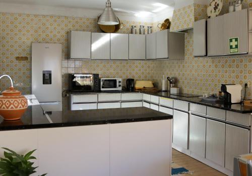 a kitchen with white cabinets and a black counter top at CLE House in Anadia