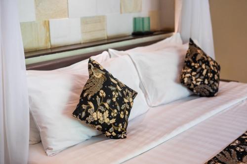 a bed with two pillows on top of it at The Maya Seminyak Villas in Seminyak