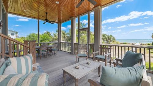 a porch with chairs and tables and a view of the ocean at Maison Blanche home by Peace Vacations in Georgetown