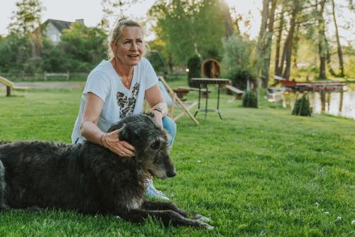 a woman sitting on the grass with a dog at Agroturystyka nad jeziorem-Herrmann hof in Dejguny
