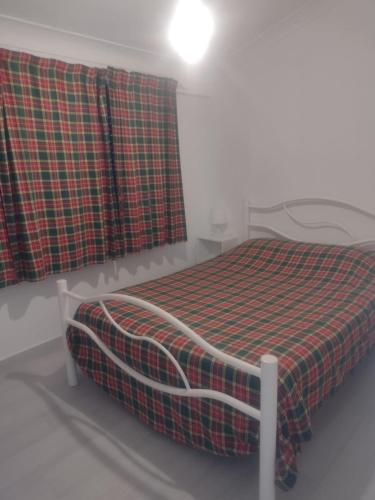 a bedroom with a bed with a plaid blanket at Casinhas de Alfenim in Sesimbra