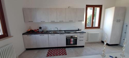 a kitchen with white cabinets and a sink and a refrigerator at Sweet Home Offida in San Giovanni in Strada
