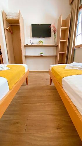 two beds in a room with a flat screen tv at Villa Deny Mostar - with free parking in Mostar