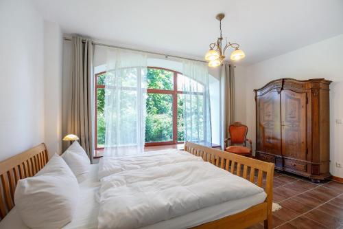 a bedroom with a large white bed and a window at Ferienwohnungen Hof Luisenau in Temmen-Ringenwalde
