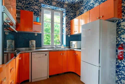 - une cuisine avec des armoires orange et un réfrigérateur blanc dans l'établissement Le Rizenn - Appt vue mer, à Bénodet
