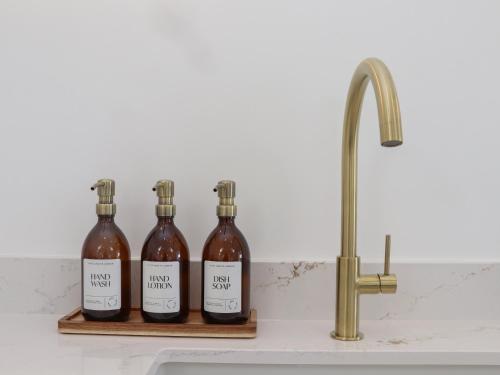 three bottles of wine sitting on a shelf next to a sink at Victory View in Penzance