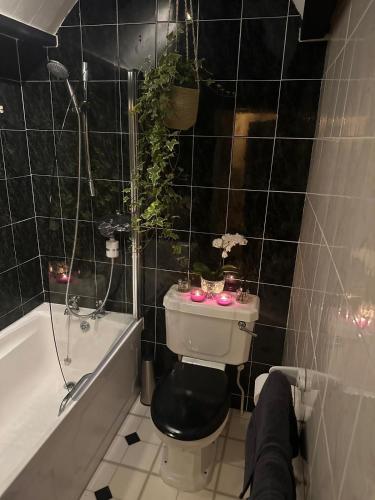 a bathroom with a toilet and a bath tub with candles at Cotswold Cottage in Steeple Aston