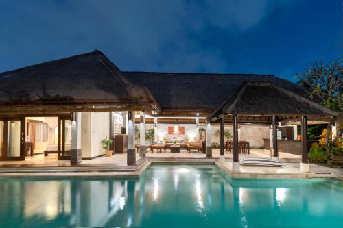 a villa with a swimming pool at night at The Maya Seminyak Villas in Seminyak