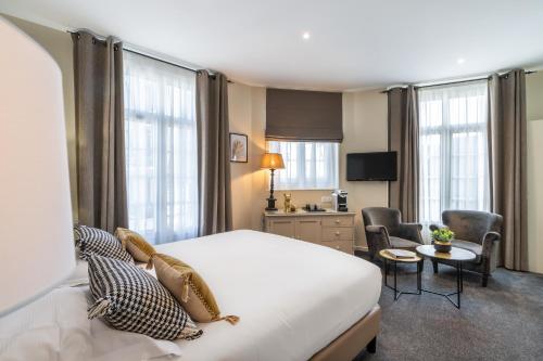 a hotel room with a bed and a living room at Hôtel Le Fer à Cheval in Trouville-sur-Mer