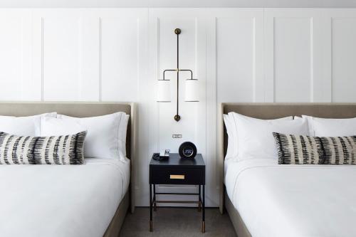 two beds with white pillows and a table between them at The Luxury Collection Hotel Manhattan Midtown in New York