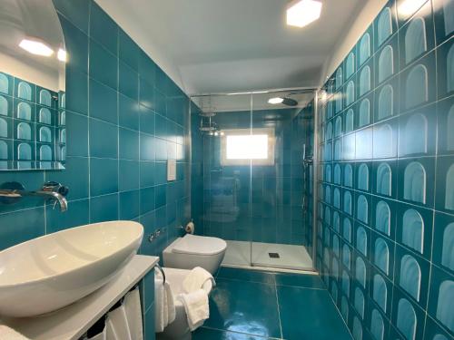 a blue tiled bathroom with a sink and a toilet at Limoni in Praiano