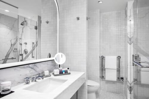 a white bathroom with a sink and a toilet at The Luxury Collection Hotel Manhattan Midtown in New York