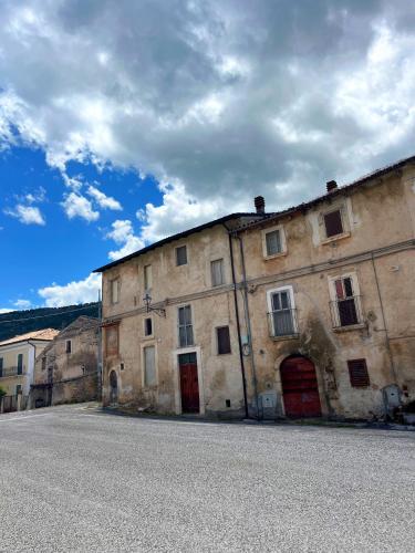 an old stone building with red doors on a street at La Locanda Del Castello in Ocre