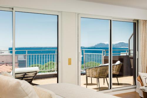 a bedroom with sliding glass doors with a view of the ocean at Hôtel Hélios in Juan-les-Pins