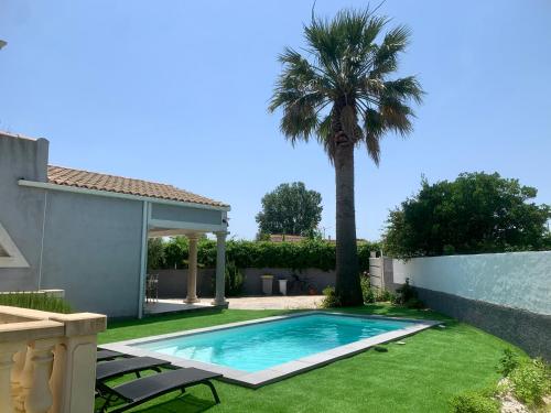 une piscine dans une cour avec un palmier dans l'établissement grande villa piscine Marseillan plage cap agde, à Marseillan